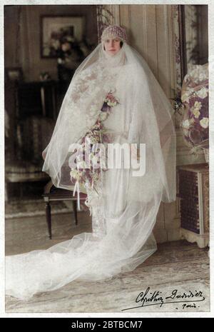1920 ca , Paris , FRANCE : A noble woman in wedding dress attire . Photo by Christian Duvivier , Paris . The photograph Duvivier was the father of most celebrated french movie director Julien Duvivier ( 1896 - 1967 ) . DIGITALLY COLORIZED . - MARRIAGE - MATRIMONIO - NOZZE - abito da SPOSA - WEDDING dress PARTY - BRIDE -  cerimonia   - FOTO STORICHE - HISTORY PHOTOS - STOCK  -SVIZZERA - hat - cappello - FASHION XX CENTURY - MODA NOVECENTO - hat - cappello cuffia - thulle - tulle - strascico  - FAMIGLIA - FAMILY - PARENTI - festa - party - ricevimento  - velo - veil - flowers - fiori - fiore - r Stock Photo