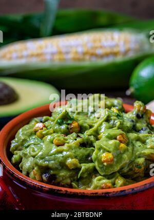 Guacamole sauce with roasted corn and raw ingredients Stock Photo