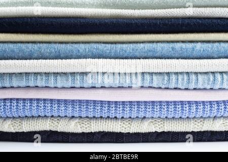 Pile of knitted winter woollen clothes sweaters of pastel colour. Cosy clothes made of wool silk cashmere, Close up Stock Photo