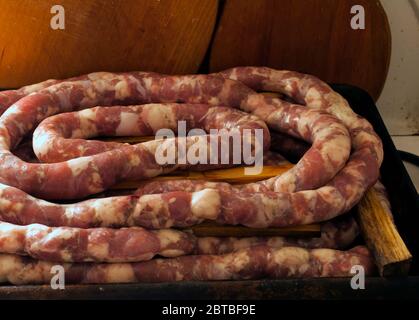 Making homemade sausage at home. Stuffing pork intestine with meat and fat. The photo shows the stage when the already stuffed raw sausage is rolled i Stock Photo