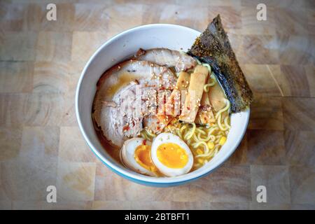 Close-up of a bowl of Hokkaido ramen in rich miso soup topped with homemade Japanese Char Siu or Japanese pork, soft yolk egg, bamboo shoots, seaweed Stock Photo