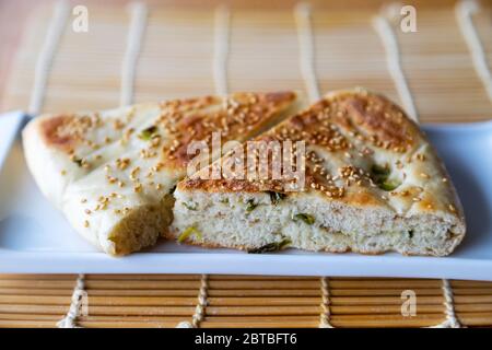 Close up of Chinese halal food known as sesame scallion bread, a popular staple in Northern China. The bread is stuffed with spring onions and topped Stock Photo