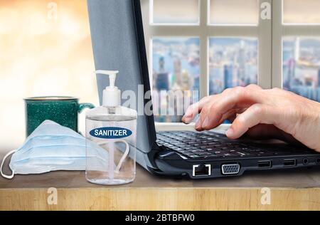 Concept of working, studying, shopping or socializing from home in the new normal after Covid-19 showing fingers on computer laptop keyboard with sani Stock Photo