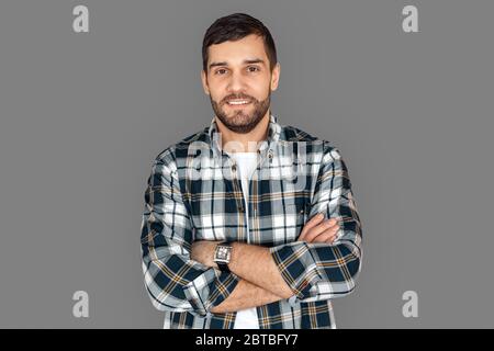 Freestyle. Young man in checkered shirt standing isolated on grey crossed arms smiling joyful Stock Photo
