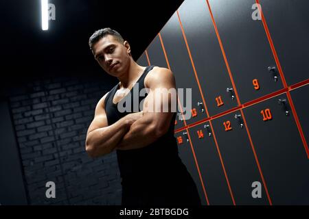 Young adult athlete man looking at camera, standing in locker room Stock Photo