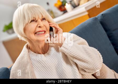 Senior woman using modern smartphone, resting at home Stock Photo