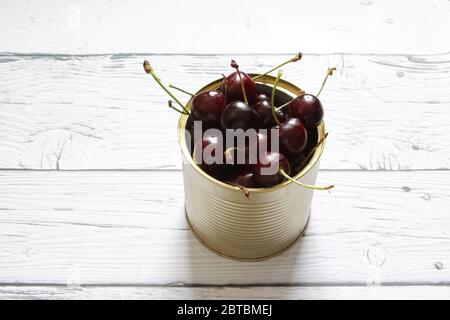 Red cherry berries in a tin can on a white background. Healthy food. Stock Photo