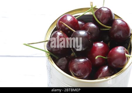 Red cherry berries in a tin can on a white background. Healthy food. Stock Photo