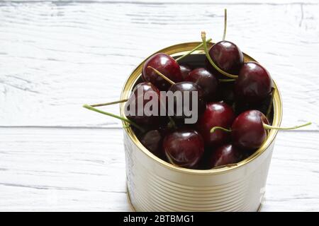 Red cherry berries in a tin can on a white background. Healthy food. Stock Photo