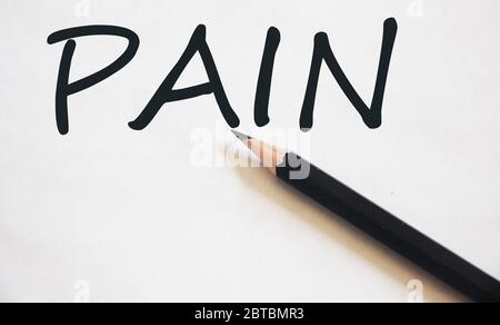 Pain word on white sheet of paper and black pencil. Relief pain healthcare concept Stock Photo