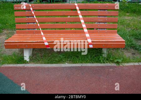 Red and white lines of barrier tape on a bench. Warning tape. The ban on walking in the park. Quarantine. Copy space for text Stock Photo