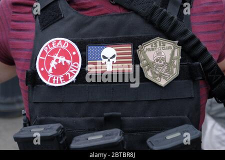 Vancouver, USA. 23rd May, 2020. A protester carrying an AR-15 assault rifle shows off his patches on a bullet-proof vest at a rally in support of the Hugga Mug Diner which re-opened today in Vancouver, Wash., on May 23, 2020. The opening is a direct violation of Governor Jay Inslee's orders for non-essential business to remain closed at this time. (Photo by Alex Milan Tracy/Sipa USA) Credit: Sipa USA/Alamy Live News Stock Photo