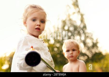 Happy child girl and boy kid playing game in backyard at summer. Happy childhood in summer days together in park. American blonde children holding Stock Photo