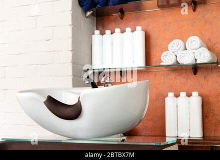 Hairdressing bowl in Beauty Salon Interior. Wash sink for washing hair, hair care spa procedures in Barber shop, shampoos, towels. Hairdresser stylist Stock Photo