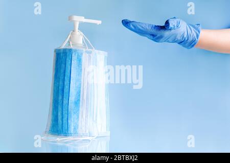 Medical face masks, surgical protective disposable mask on bottle alcohol gel to sanitize doctor hands in gloves. Coronavirus covid 19 virus Stock Photo