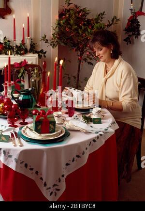 Woman wrapping gifts at table set for Christmas dinner EDITORIAL USE