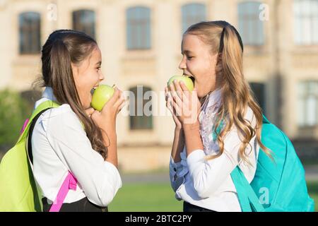 Apples good for teeth. Happy girls eat apples outdoors. Green apples for school snack. Healthy food. Vitamin source. Organic and natural eating. Apples are nutritious. Health benefit. Stock Photo
