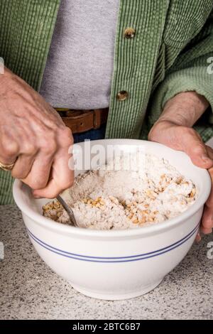 Woman stirring dry ingredients in preparation for making sprouted wheat bread Stock Photo