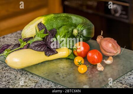 Gather your ingredients needed to make your veggie pizza toppings.  Fresh is always tastier.  In this picture are zucchini, summer squash, basil, toma Stock Photo