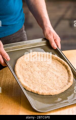 This multi-grained pizza crust has just been stretched to the desired size with a pinched rim to hold the toppings on, and is ready to rise, and be pa Stock Photo