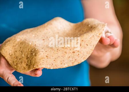 Stretching the multi-grain pizza dough on your hands to make a thin-crust pizza Stock Photo