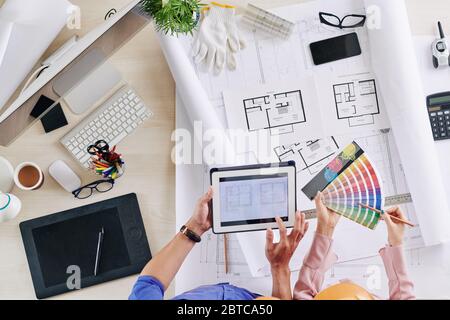 Architects discussing building blueprint and color palettes for walls and ceiling Stock Photo