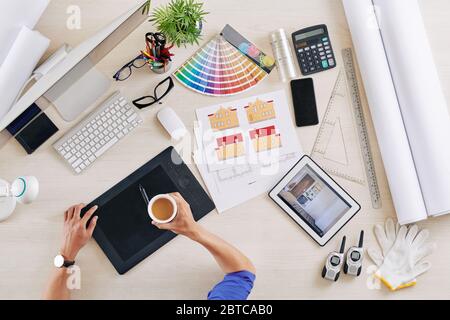 Interior designer drinking cup of coffee when working on project of building and room design Stock Photo