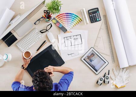 Interior designer drinking cup of coffee and talking on phone with client, view from above Stock Photo