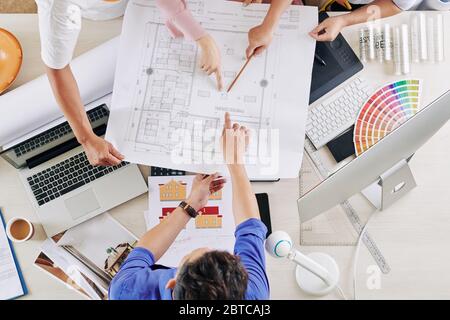 Team of architects and designers pointing at blueprint of commercial building they are working on Stock Photo