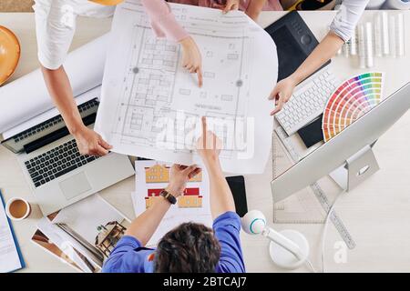 Group of architects pointing at blueprint of building, view from above Stock Photo