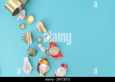 Metal garbage flies out of a metal can on the blue background. Waste separation concept. Flatlay, copy space. Stock Photo