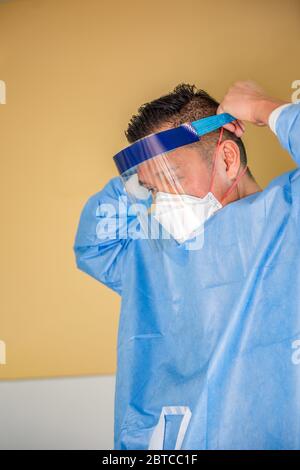 A health care worker prepares to treat a contagious patient by putting on personal protective equipment in portrait format. Stock Photo