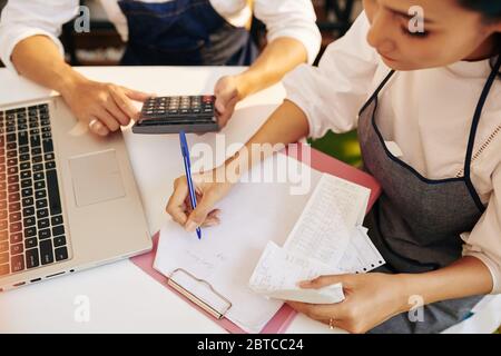 Cafe owners checking bills and receipts, taking notes and making calculations Stock Photo