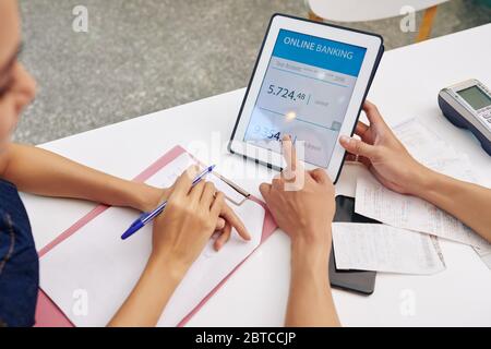 Small business owners discussing debt to the bank they need to pay when checking bank account via application on tablet computer Stock Photo