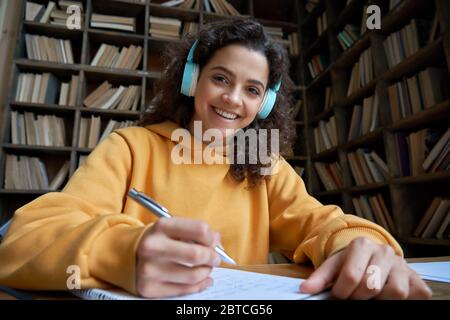 Smiling hispanic teen girl student looking at webcam distance learning. Stock Photo