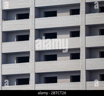 Construction site. Unfinished apartment building made of white bricks. Empty windows and balconies. Stock Photo