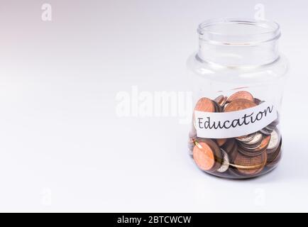 Money jar labelled education containing pennies on white background and copy space Stock Photo