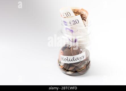 Travel money savings in a transparent jar filled with UK pennies and Sterling currency Stock Photo