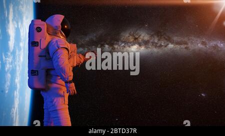 astronaut presenting an empty space in front of planet Earth and the Milky Way galaxy Stock Photo