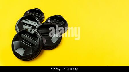 Coffee balck cover lids lay on each other on yellow background. Stock Photo