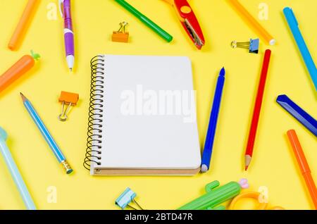 Colored different school supplies on soft yellow paper background. Notebook, pens, pencils and other tools. Back to school background. Flat lay, top v Stock Photo