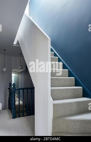 White staircase with ribbed wooden slat design. Long House, London, United Kingdom. Architect: R2 Studio , 2018. Stock Photo