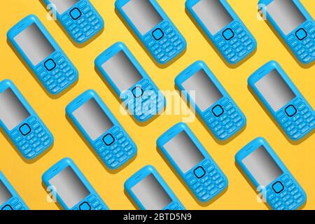 Colorful blue mobile phone background pattern with repeat cellphone icons in diagonal rows over a bright yellow background Stock Photo