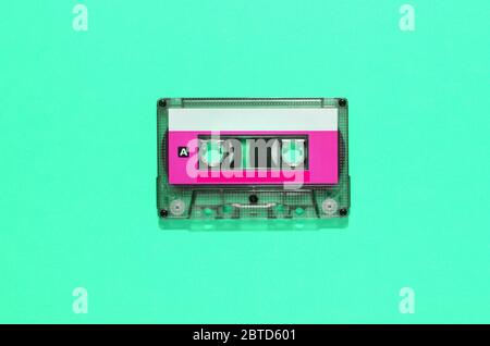 Vintage audio tape in plastic cassette with colorful blank label centered over a green background with copy space in a flat lay still life Stock Photo