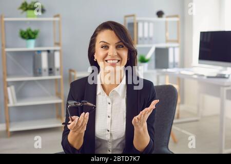 Woman businessman smiling looking at the camera gives a lecture online conference blog gesturing with his hands in a living apartment. Stock Photo