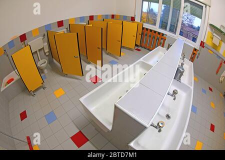 interior of the public bathroom of a kindergarten without children with small sinks and yellow doors photographed with fisheye lens Stock Photo