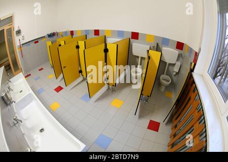 Interior of Empty bathroom of a daycare center with small yellow doors and white ceramic sink photographed by fisheye lens without children Stock Photo