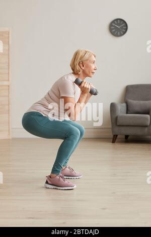 Senior woman exercising with dumbbells during sports training at home Stock Photo