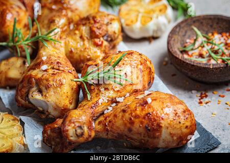 Fried spicy chicken legs with herbs and garlic on black slate, dark background. Stock Photo
