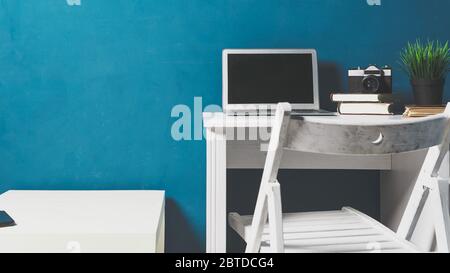 Empty workplace. Work from home. Notebook, books and pencil holder on the table on a background of blue background. Modern work environment and remote Stock Photo